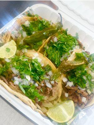 Grilled asada tacos topped with raw onions and cilantro