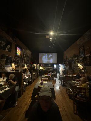 Movie screens at both ends of restaurant allow all to see the show.