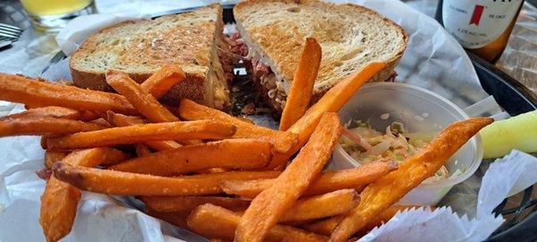 Reuben sandwich with sweet potatoes fries, coleslaw and a pickle.