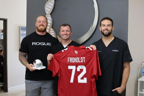 Hjalte Froholdt with Dr. Trever Wilkins and Carter Kerber in office holding signed jersey that will be hung up in our office