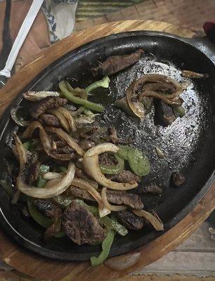 Sizzling, somehow cold, dry steak fajitas.