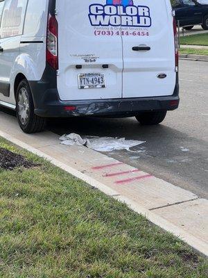 Spilled paint covered with drop cloth and left in street .