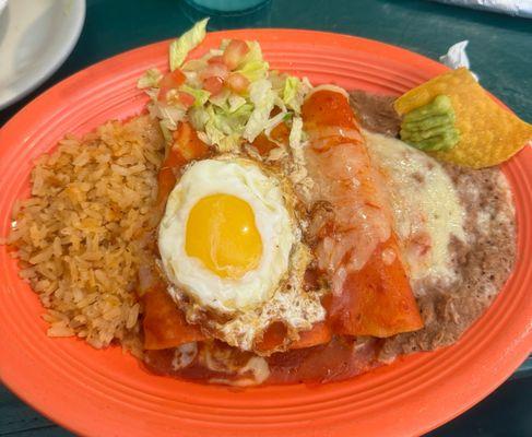 Baked red chicken enchiladas with sunny side egg on top.