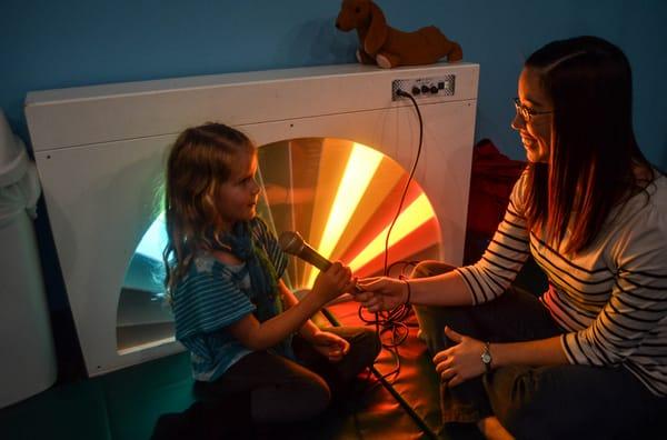 Therapist Megan helps Simone use the voice activated fan light. The fan light is one of many pieces of specialized equipment.