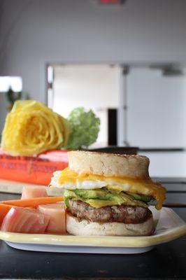 Egg and cheese breakfast sandwich, with sausage and avocado.