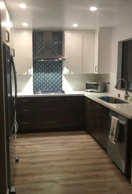 Kitchen renovation in a small condominium. Modern Drama is created with dark wood lower cabinets, and stunning glass tile focal point.