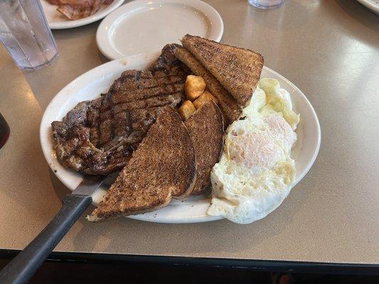 Steak and Eggs with Wheat Toast and breakfast potatoes.