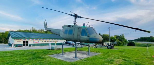 A Huey helicopter and a howitzer are in front of the Stars and Stripes Museum Library