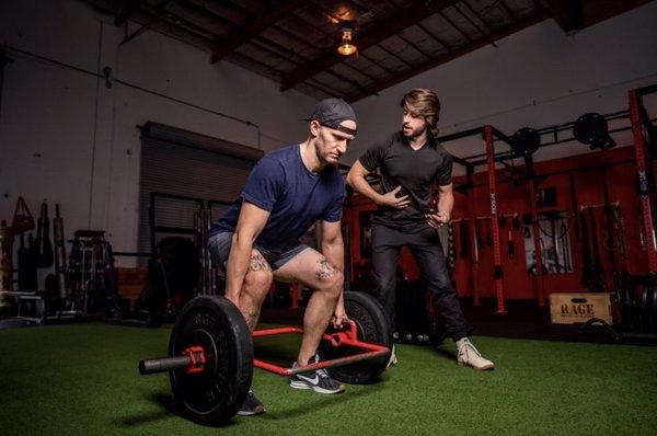 Zach coaching a client on proper deadlift form.