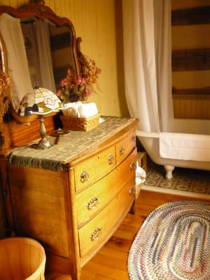 Antique claw-foot tub with shower and pedestal sink.