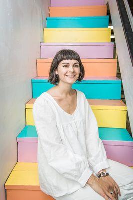 Alexa here. Sitting on the rainbow stairs that lead up to the sewing studio. Wearing a handmade shirt.