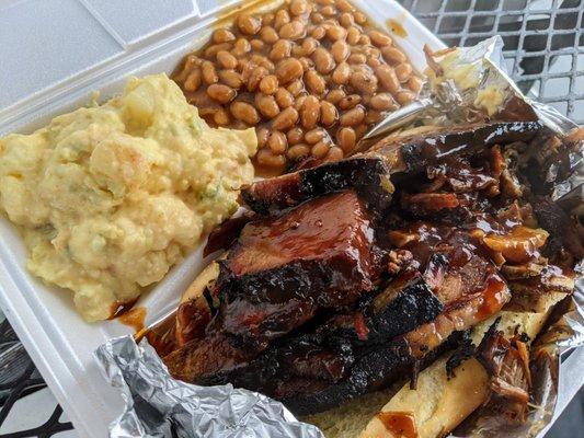 Smoked Beef Brisket BBQ Sandwich with potato salad and baked beans.