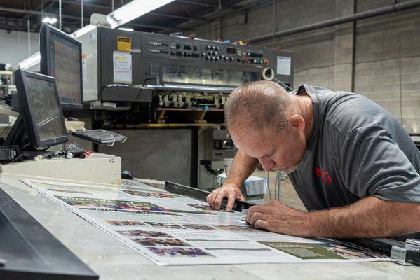 Expert pressman inspecting press sheet for top quality printing.