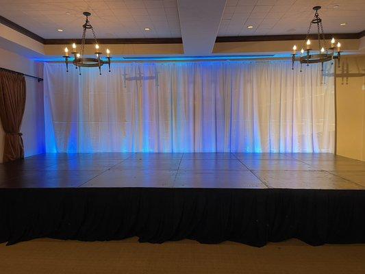 Stage, white drape pipe and base, blue/cyan uplighting