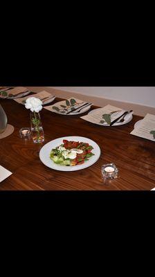 Dinner setting with caprese salad dressed table side.