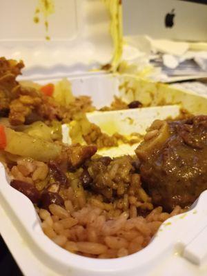 A mostly eaten helping of curry goat. Comes with rice & peas and steamed veggies (cabbage & carrots I think). This is a small.