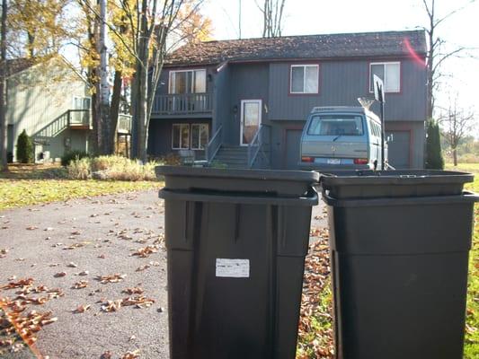 Garbage cans left out, with an abandoned 1989 VW van parked in the driveway, but stuck in the mud