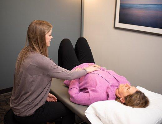 Physical therapist providing exercise instruction and assessing pelvic health condition.