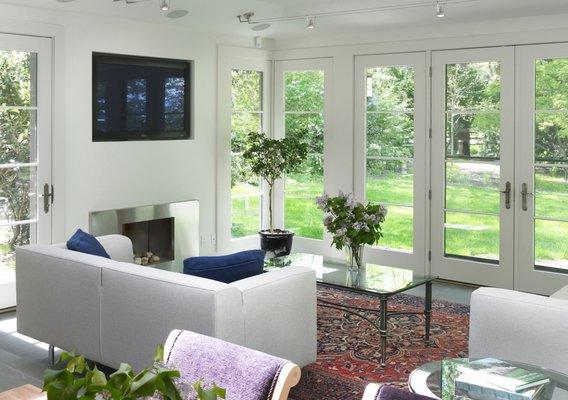 Tall glass doors ensure that natural light permeates the entirety of this living room.