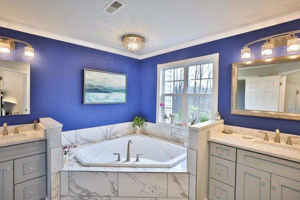 Master bathroom remodel with corner bathtub & marble lined tiles