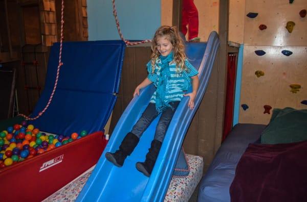 Simone goes for a ride down the slide in the Kid's Creek Therapy Exploration Room.