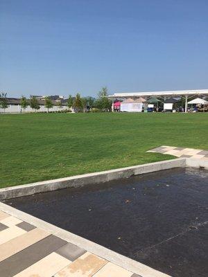 Flat green with farmers market in session in the background.