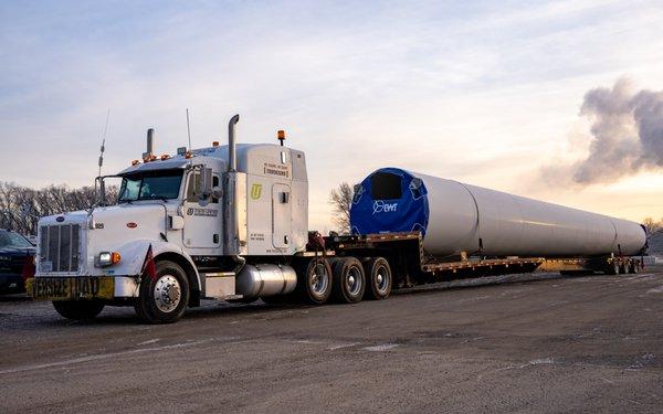 Windmill tower sections on stretch trailers.