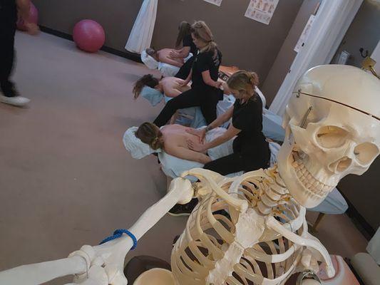 Adam taking a selfie in the lab with students practicing massage and prepping for Texas massage state board