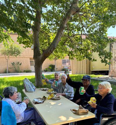 Some of our residents enjoyed a picnic at the park, sitting around a table under the shade of a tree.