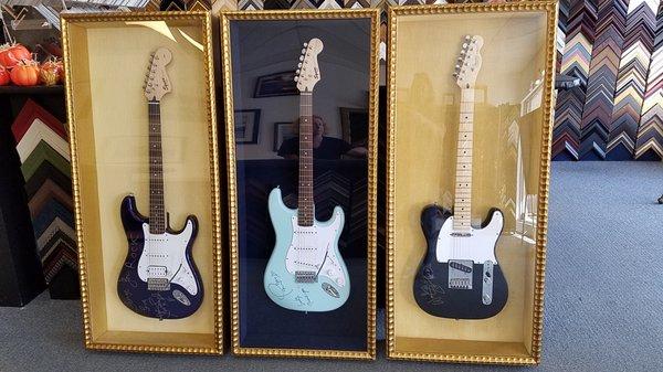 electric guitars mounted on to velvet backing and framed in a gold sahdowbox