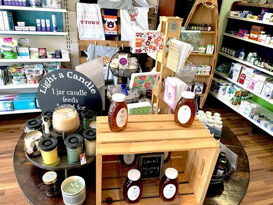 Display table of assorted  products like local honey, scented candles, goat's milk soap and more.