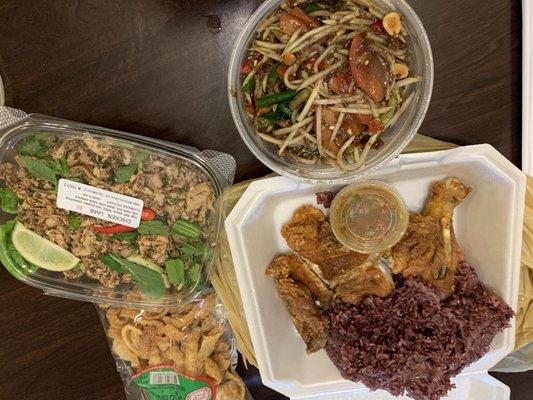 From left, laab chicken, papaya salad, fried chicken quarter with purple sticky rice