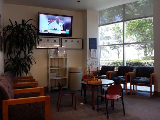 Corner of waiting room has a flat screen TV running at all times. There is also a round kiddies table and activity block.