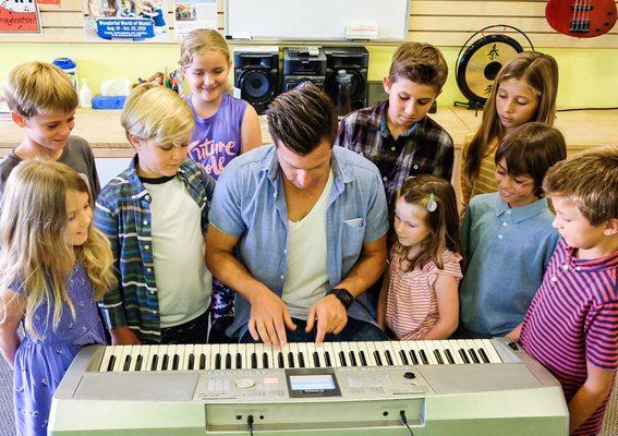 Mr. Brett shows the students how to play a song.