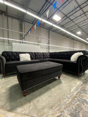 Beautiful black sectional sofa with white fluffy pillows and ottoman.