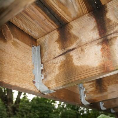 These deck joist hangers have missing nails, possibly causing a collapse.