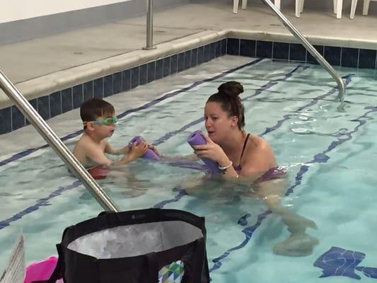 Miss Kelly making the pool noodle "talk" to my son.