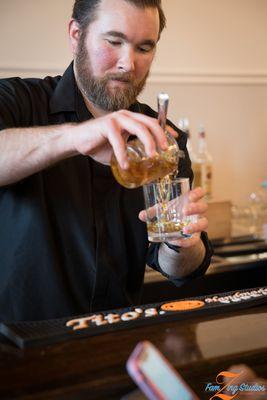 A Liquid Catering bartender pouring a dark liquor