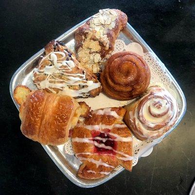 Clockwise from right: Cinnamon Roll; Raspberry Danish, Ham and Cheese Croissant; Blueberry Scone; Almond Croissant; Morning Bun.