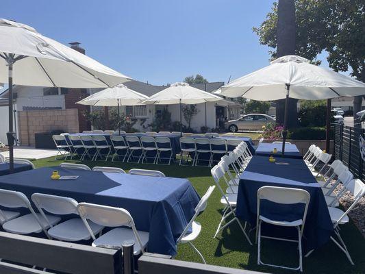 Front yard set up with tented tables, chairs and umbrellas.