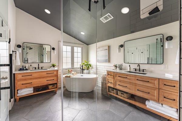 Huge Hexagon tiles on the floor. Free standing bathtub and wood look custom vanities with black fixtures