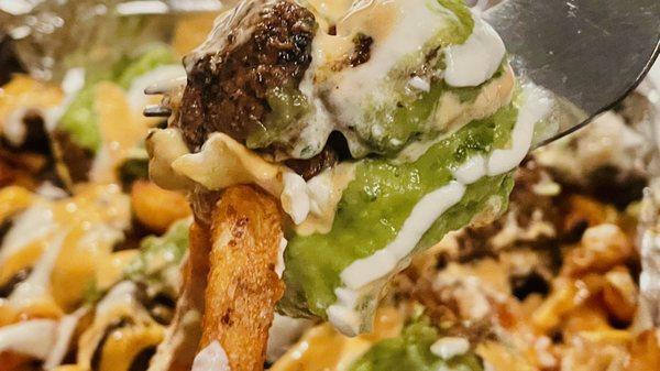 SoCal Asada fries: curly fries, cheese, sour cream, guacamole, cilantro, grilled onions, grilled jalapeno, and sauce. $16.95.