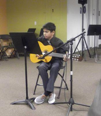 Student playing guitar at recital