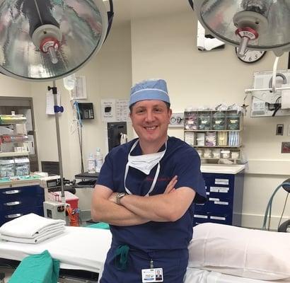 Dr. Brian D. Cohen from Cohen Plastic Surgery wearing medical scrubs in his surgical suite after completing a procedure.