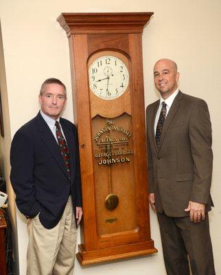 Craig and Bill standing with the antique clock at the entrance of the agency which was founded in 1955