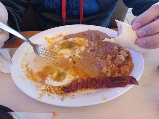 Juevos Rancheros with green table salsa on top, beans, papas (comes with Ranchero sauce on top), bacon, and HUGE tortillas.