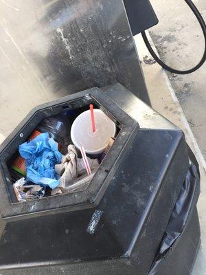 Typical: very full trash and lots of debris on ground a customer had to step around as he pumps gas.