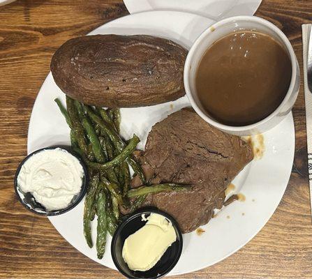 Pot roast with side of gravy baked potato and asparagus