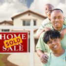 African American Family in Front of House and Sold Sign