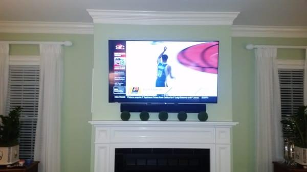 This is a 70" 4K TV wall mounted over a fireplace with a sound bar mounted on an articulating bracket.